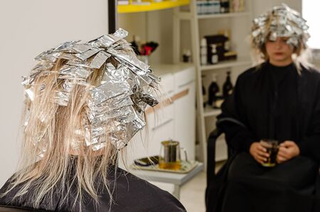 Foil on models hair. Bleaching or dyeing process. Beauty salon, fashionable hair coloring with AirTouch techniqueの写真素材
