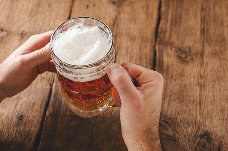 Male hands holding full glass of blonde beer. Leasure concept. Copy spaceの写真素材