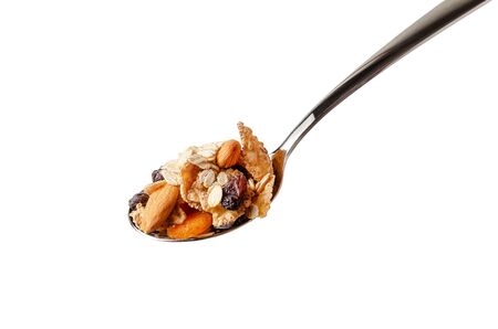 Metal spoon with fiber flakes, oats,almond and dried fruits. Isolated on white background.の写真素材