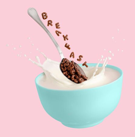 Cocoa cereal letters falling into blue bowl with splashing milk. Breakfast for children. Isolated on pink background.の写真素材