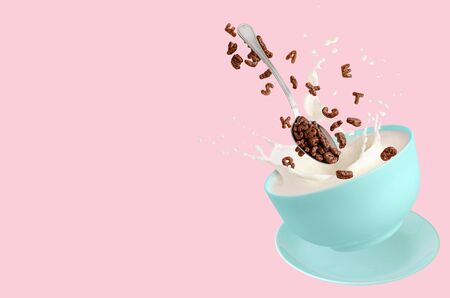 Cereal cocoa letters falling into blue bowl with splashing milk on pink background. Dry breakfast for children. Copy space.の写真素材