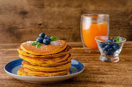 Stack of pumpkin pancakes with blueberries on rustic wooden background. Copy space.の写真素材