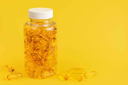Fish oil and vitamin E supplement capsule on yellow background.の写真素材