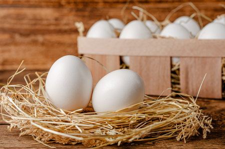 Fresh chicken eggs on hay on wooden background. Organic food