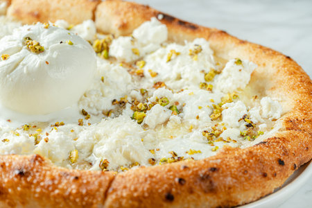 Close up of cheesy pizza of six kinds of cheese and pistachios. Italian food