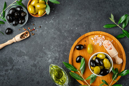 Olive oil and olives with leaves and pink salt on dark background. Overhead, copy spaceの写真素材