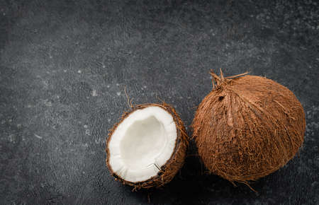 Whole and a half of cracked coconut on dark concrete background. Copy space, top viewの写真素材