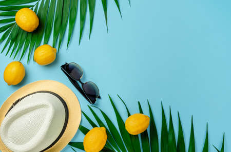 Hat, sunglasses and lemons with palm leaves. Summer background, flat lay.の写真素材