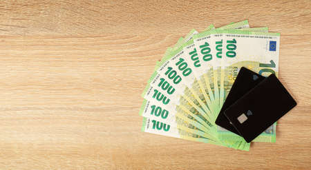 Cash versus credit cards. Euro currency on wooden background.の写真素材