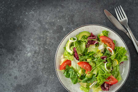 Fresh vegetarian salad on dark stone background. Top view, copy space.の写真素材