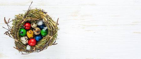 Decorated Easter quail eggs in a nest on white wooden background. Copy space