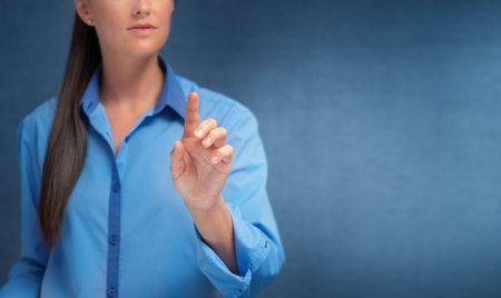 Female hand touching the virtual screen with index finger on blue background. copyspace.の写真素材