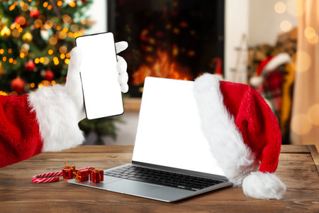 Notebook and smartphone with blank screen on rustic Christmas interior with fireplace. Christmas online shopping.の写真素材