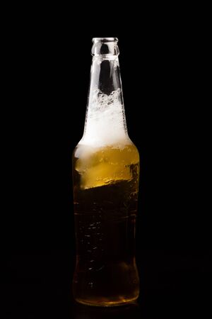 Open bottle of light beer with foam on a black backgroundの写真素材