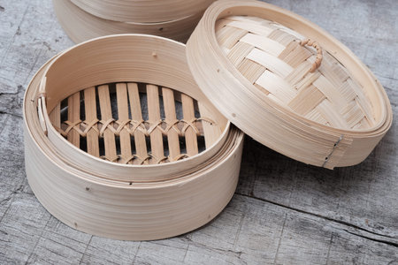 Isolated empty round steamer bamboo basket or bamboo crate on wooden table topの写真素材
