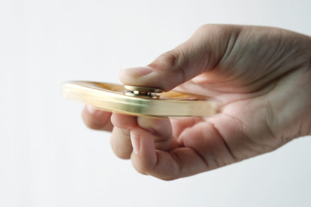 Isolated hand spinning goldren metal fidget finger spinner on white backgroundの写真素材