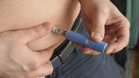 obese fat man preparing Semaglutide Ozempic injection control blood sugar levelsの写真素材