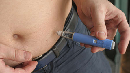 obese fat man preparing Semaglutide Ozempic injection control blood sugar levelsの写真素材