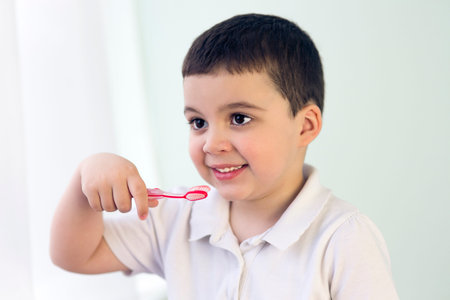 kid boy brushing teeth and looking at mirror