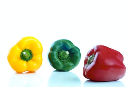 three differently colored peppers on a white backgroundの写真素材