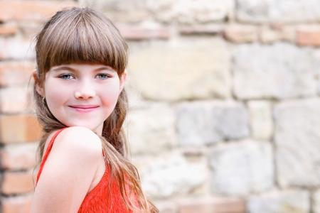 Portrait of a young girl by the stone wallの写真素材