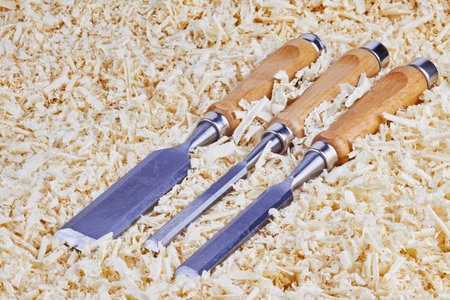 Three chisels of various widths lying in wooden shavings