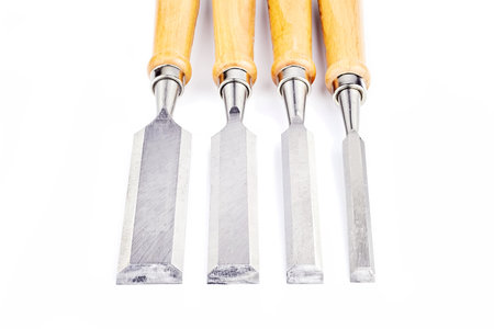Four chisels of various widths lying on a white background