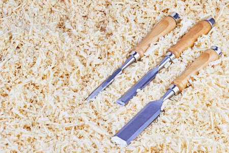 Three chisels of various widths lying in wooden shavings