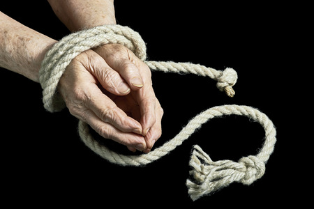 View of the old hands tied with rope on a black backgroundの写真素材