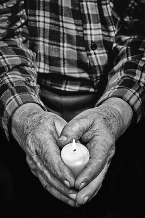 View of an old man hands holding a burning candleの写真素材