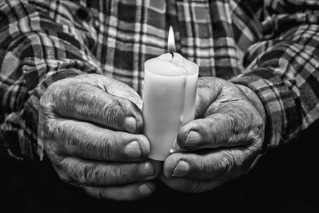 View of an old man hands holding a burning candleの写真素材