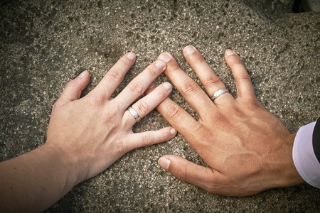 Newlyweds hands with rings on stoneの写真素材