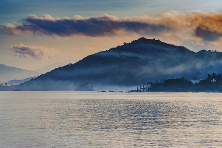 A morning foggy morning on Lombok beach with a mountain in the backgroundの写真素材