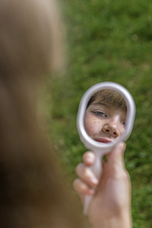 Portrait of young girl looking in the mirrorの写真素材
