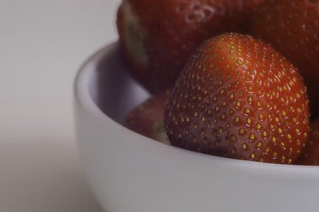 Closeup view of a group of fresh strawberries in a white bowlの写真素材