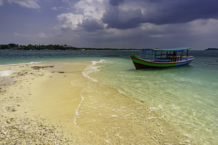 Tourist boats on the shore of a sandy beach with clouds in the backgroundの写真素材