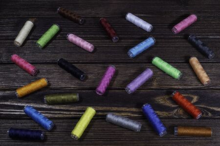 Group of differently colored spools perching on a wooden table topの写真素材