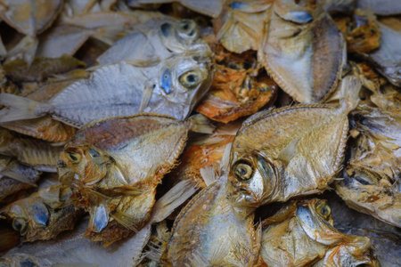 A detailed close-up of several dried fish laid together, showing textures, eyes, and fins, often...