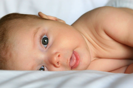 Happy baby smiling on white sheets 
