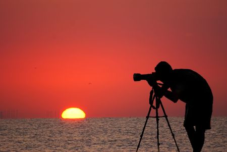 This is a man taking pictures during the sunrise.の写真素材