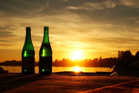 These are two bottles of champagne with sunset in background.の写真素材