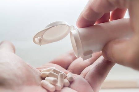 White Pills spill out of container on handの写真素材