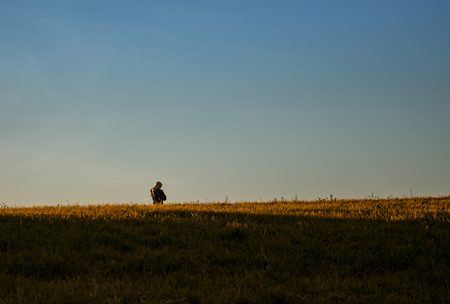 Minimalistic hillside scene in late summer, Young woman at distanceの写真素材