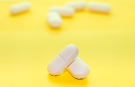 White prescription pills on yellow background close upの写真素材