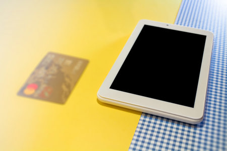Online shopping background. tablet screen with copy space low view on yellow-blue background credit...