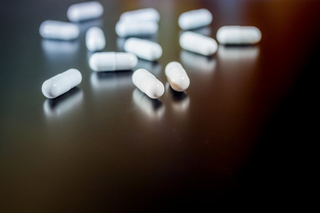 White Pills isolated on shiny black backgroundの写真素材