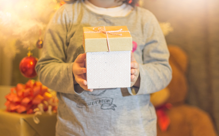 Little girl holding Christmas present in hands at home selective focusの写真素材