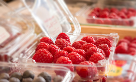 Plastic box with raspberries on marketの写真素材