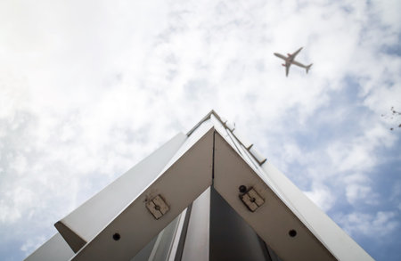 Corner of steel frame building against cloudy sky and airplane