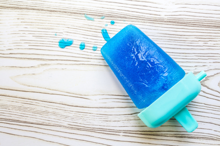 Blue Blueberry ice pop melts on wooden backdropの写真素材